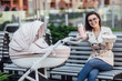 © Тарас Нагирняк - Pretty brunette mom sitting with stroller and holding lunch box with eat from her baby in the park.