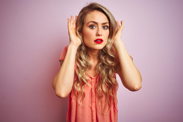 Sticker - Young beautiful woman wearing t-shirt standing over pink isolated background Trying to hear both hands on ear gesture, curious for gossip. Hearing problem, deaf