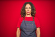 © Krakenimages.com - Middle age senior woman wearing apron uniform over red isolated background skeptic and nervous, frowning upset because of problem. Negative person.
