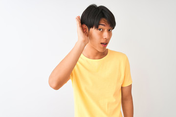 Wall Mural - Chinese man wearing yellow casual t-shirt standing over isolated white background smiling with hand over ear listening an hearing to rumor or gossip. Deafness concept.