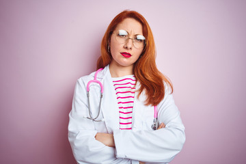 Sticker - Young redhead doctor woman wearing glasses over pink isolated background skeptic and nervous, disapproving expression on face with crossed arms. Negative person.