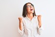 © Krakenimages.com - Young beautiful businesswoman wearing glasses standing over isolated white background celebrating surprised and amazed for success with arms raised and eyes closed. Winner concept.