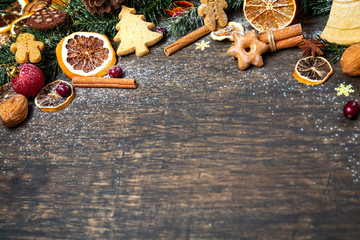 Wall Mural - Christmas background with Christmas tree branch, festive decoration, dry fruits, home made cookies and traditional seasonal spices, top view