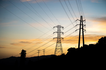 Transmission electrical lines silhouetted against sunset in Los Angeles, CA