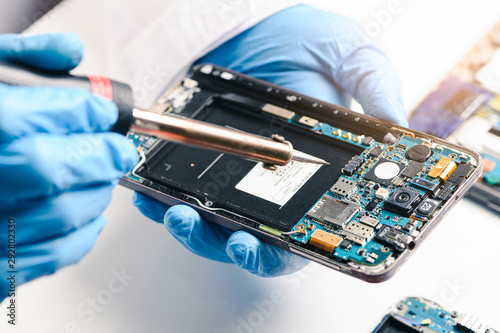 Fotomural The technician repairing the smartphone's motherboard in the lab by soldering method