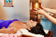 Young woman having pouring oil massage spa treatment. Shirodhara