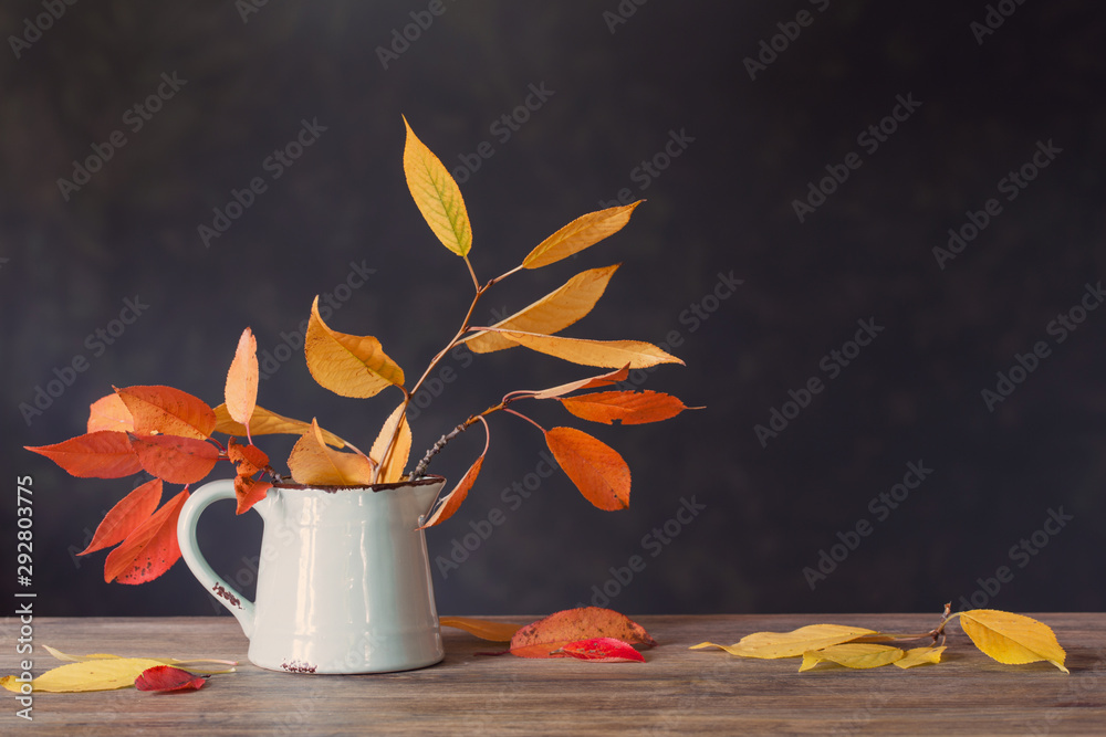 Obraz na płótnie autumn leaves in jug on wooden table on dark background w salonie