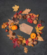 autumn background. harvest season. empty Paper tag, acorns, leaves, nuts, pumpkins and cones on dark table. autumn holiday, fall time, thanksgiving, halloween concept. copy space