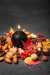 beautiful mysterious scene with candle. magic black candle with autumn leaves, cones, acorns. Halloween, Samhain and Thanksgiving decoration on dark table. conceptual autumn background. fall season.