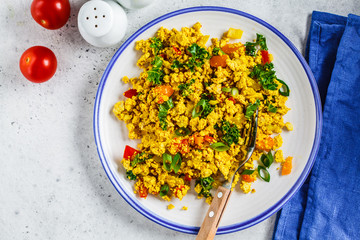 Wall Mural - Tofu scramble with vegetables in a white plate, top view. Vegan Alternative fried eggs.