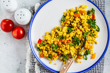 Wall Mural - Tofu scramble with vegetables in a white plate, top view. Vegan Alternative fried eggs.