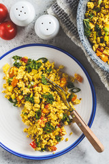 Wall Mural - Tofu scramble with vegetables in a white plate, top view. Vegan Alternative fried eggs.