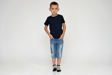 Full-length portrait on a white background of a cute boy child with Vitiligo disease - a violation of the color of the skin at the initial stage. Black T-shirt, blue jeans.