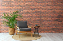 Modern Room Interior With Stylish Grey Armchair And Potted Plant Near Brick Wall