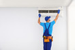 © New Africa - Professional technician maintaining modern air conditioner indoors. Space for text