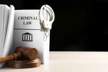 Wall Mural - Judge's gavel, Criminal Law book and handcuffs on white table against black background. Space for text