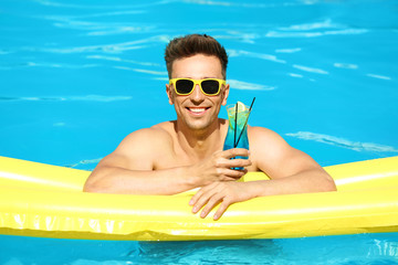 Canvas Print - Happy young man with cocktail and inflatable mattress in swimming pool