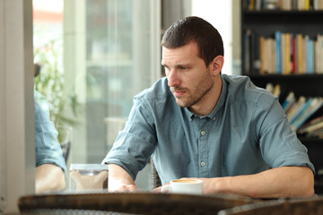 Sad adult man looking down in a coffee shop