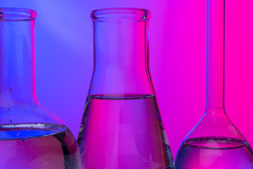 Chemical glassware close up on neon pink-purple background