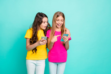 Sticker - Photo of funny casual nice cute friendly couple of blonde brunette girlfriends wearing pink yellow t-shirts getting shocked with something oh their phones while isolated with teal background