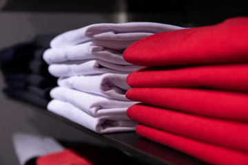 Wall Mural - Red and white men clothing on shelf. T-shirt on rack for sale in shop. Autumn seasonal wear in department store.