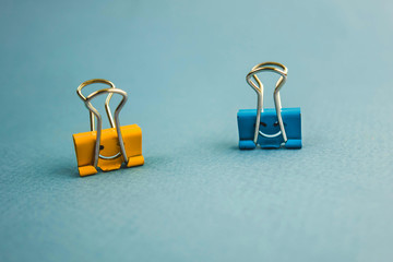 two paper clips in blue and orange with a smiley face on a blue background