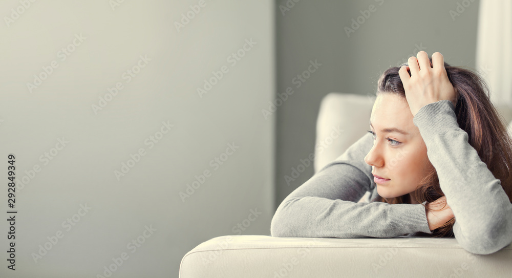 Depressed young woman on sofa at home. - obrazy, fototapety, plakaty 