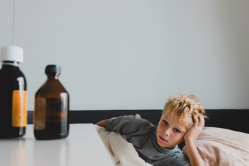 Sick child with fever at home, medicines on the table