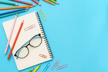 Wall Mural - flat lay photo of office desk with colorful pencil, paper clip, note book, glasses, top view of the 