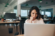 © mavoimages - Young businesswoman sitting at her desk working on a laptop