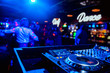 control DJ for mixing music with blurred people dancing at party in nightclub