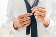 partial view of man in white shirt tying tie