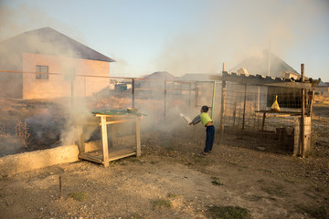 Wall Mural - Dry grass burns in a field with smoke, and a young boy tries to put out the fire