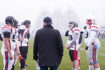 american football players discussing strategy with coach