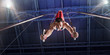 Male athlete doing a complicated exciting trick on gymnastics rings in a professional gym. Man perform stunt in bright sports clothes