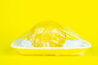 Fresh food in plastic package recycling and environment eco problem concept. Lemon wrapped in plastic on yellow background