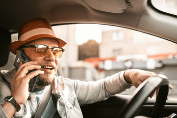 Portrait of casual man in sunglasses drive taxi car and talk on telephone. Transportation. Car driver in sunglasses on the road in summer sunset. Trip