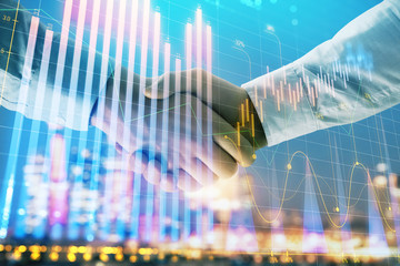 Double exposure of financial chart on cityscape background with two businessmen handshake. Concept of financial analysis and investment opportunities