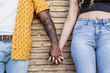 interracial couple holding hands on a brick wall