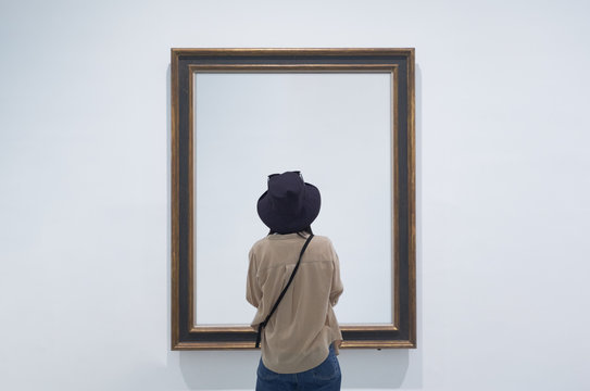 interior view of a lonely girl or tourist looking at blank canvas at a museum or gallery.