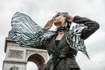Outdoor autumn fashion portrait of elegant, luxury lady wearing trendy black boucle blazer, wide leather belt, animal, zebra print silk scarf, posing near Triumphal Arch in Paris. Copy space