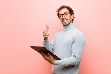 young handsome man with a tablet against pink flat wall