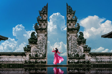 young woman standing in temple gates at lempuyang luhur temple in bali, indonesia. vintage tone.