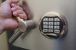 The man's hand opens the armored door of the safe with a digital code lock.