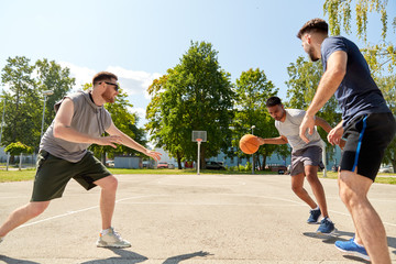 Wall Mural - sport, leisure games and male friendship concept - group of men or friends playing street basketball