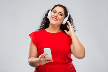 Wall Mural - people, electronics and technology concept - happy woman in wireless headphones listening to music on smartphone over grey background