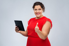 Technology, People And Internet Concept - Happy Woman In Red Dress Using Tablet Pc Computer Showing Thumbs Up Over Grey Background