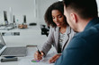 © StratfordProductions - Close-up of young female executive discussing business plan to her colleague with graph and chart on desk