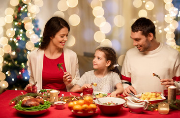 Canvas Print - holidays, family and celebration concept - happy mother, father and little daughter having christmas dinner at home