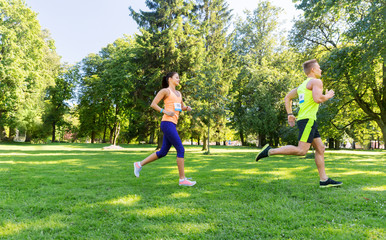 Poster - fitness, sport, race and healthy lifestyle concept - happy couple of sportsmen running marathon with badge numbers at summer park